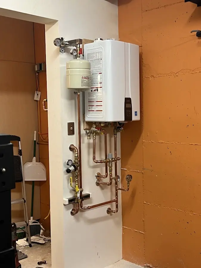 Plumbing technician inspecting water heater connections in Irwin